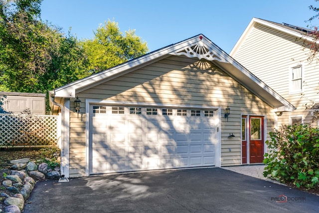 view of front facade featuring a garage, fence, and aphalt driveway