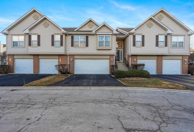 view of front of property featuring driveway, an attached garage, and brick siding