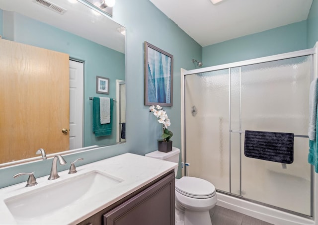 full bathroom with toilet, vanity, a shower stall, and visible vents