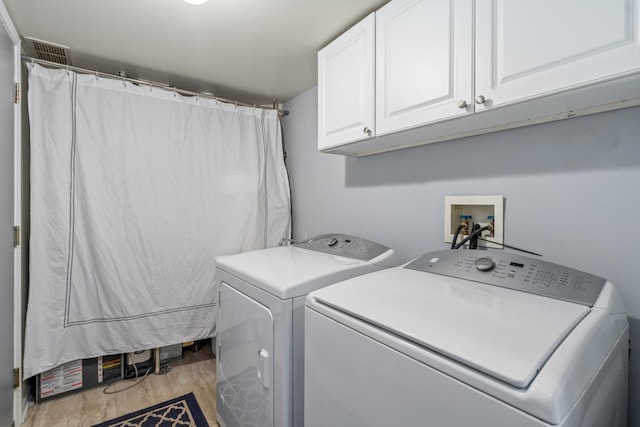 washroom featuring cabinet space, washing machine and dryer, visible vents, and light wood finished floors