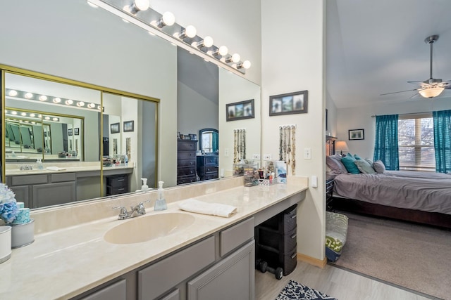 bathroom with wood finished floors, vanity, a ceiling fan, vaulted ceiling, and ensuite bath