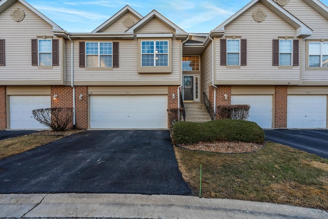 view of front of home with driveway, an attached garage, and brick siding