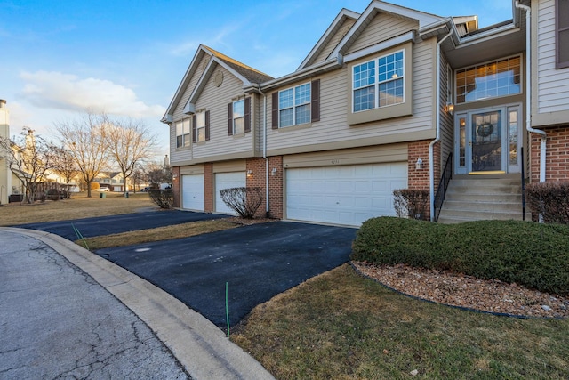 view of front facade with driveway, a garage, and brick siding