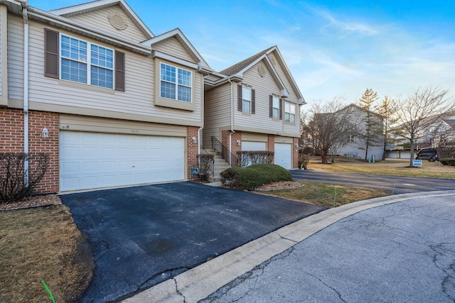 view of front facade with brick siding, an attached garage, and aphalt driveway