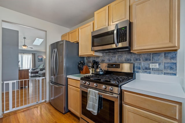 kitchen featuring light countertops, appliances with stainless steel finishes, light brown cabinets, and tasteful backsplash