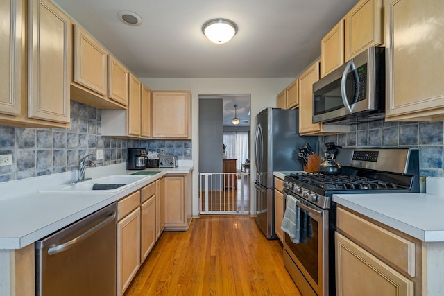 kitchen featuring light brown cabinets, appliances with stainless steel finishes, light countertops, and a sink