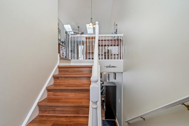 stairs featuring a notable chandelier, wood finished floors, and baseboards