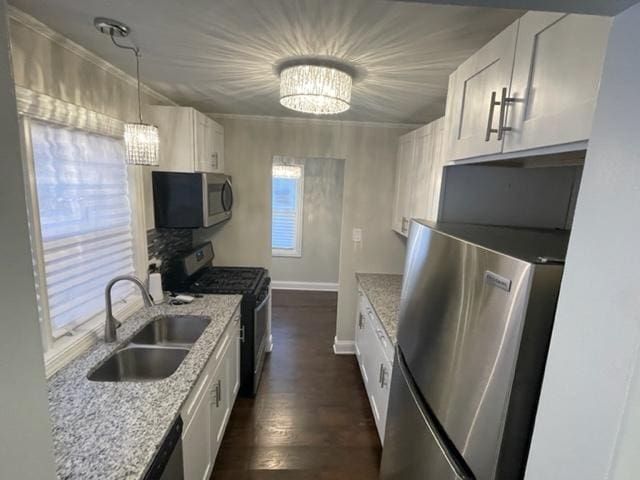 kitchen with stainless steel appliances, white cabinets, a notable chandelier, and a sink