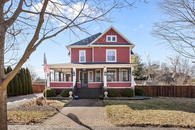 view of front of property featuring a sunroom, fence, and a front lawn