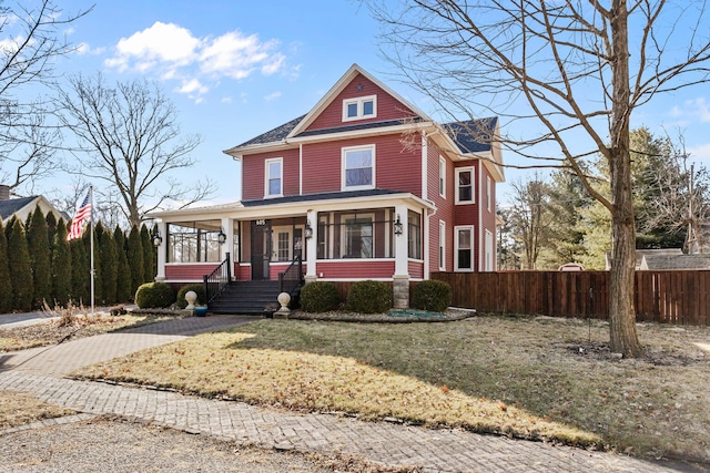 view of front of house with covered porch, a front lawn, a chimney, and fence