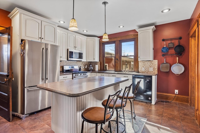 kitchen with decorative light fixtures, backsplash, appliances with stainless steel finishes, a kitchen island, and a kitchen bar