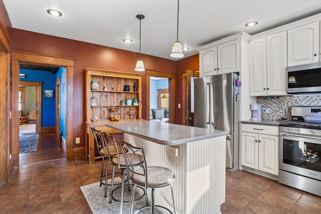 kitchen with a breakfast bar area, stainless steel appliances, white cabinetry, a center island, and tasteful backsplash