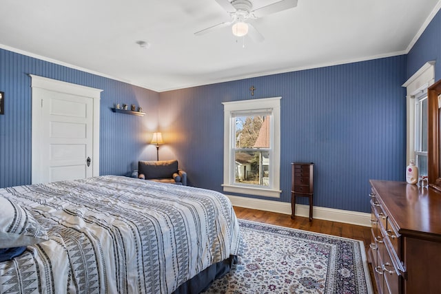 bedroom featuring dark wood-style floors, ornamental molding, baseboards, and a ceiling fan