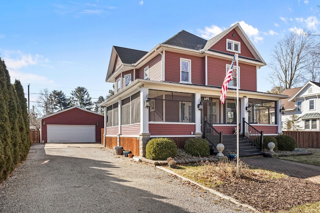 view of front of house featuring a garage, a sunroom, fence, and an outbuilding