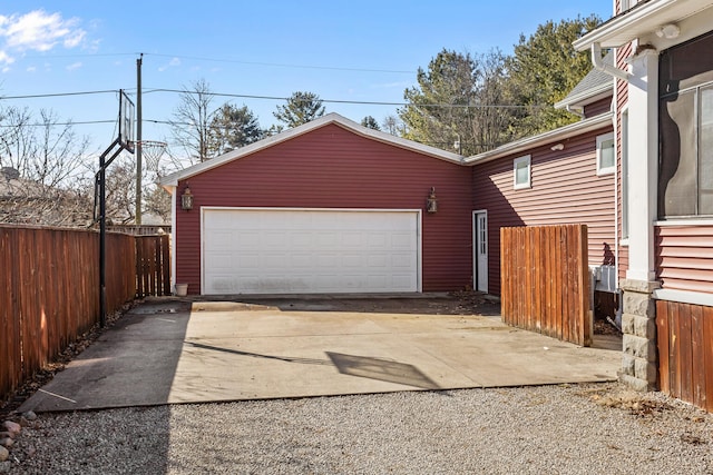 garage with gravel driveway and fence