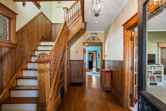 stairway with wooden walls, visible vents, a wainscoted wall, hardwood / wood-style flooring, and crown molding