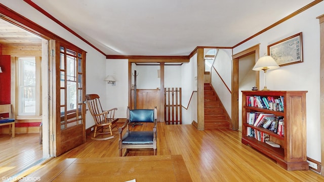 living area with light wood-type flooring, stairs, and crown molding