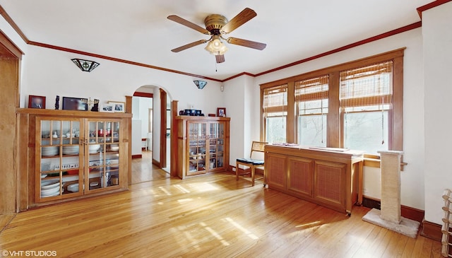 office area featuring arched walkways, crown molding, baseboards, and light wood-style floors