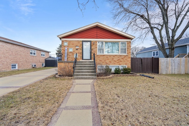 view of front of property with a front yard, fence, and brick siding