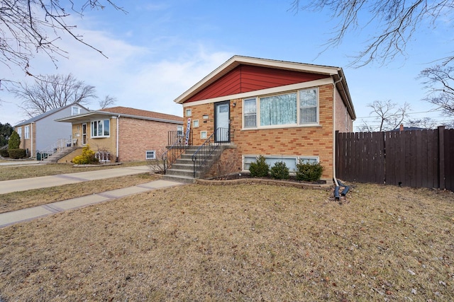 view of front of property with brick siding, a front lawn, and fence