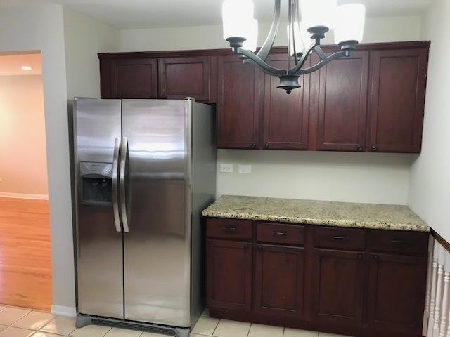 kitchen featuring light stone countertops, baseboards, stainless steel refrigerator with ice dispenser, and light tile patterned flooring