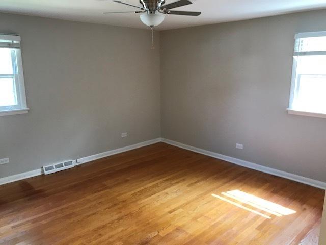 spare room with baseboards, visible vents, ceiling fan, and wood finished floors