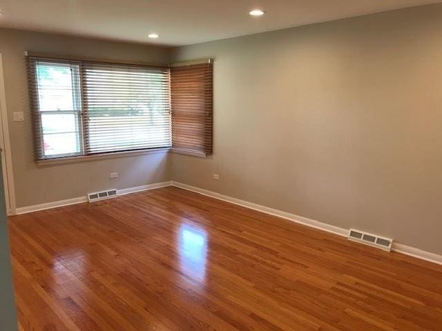 unfurnished room featuring recessed lighting, wood finished floors, visible vents, and baseboards