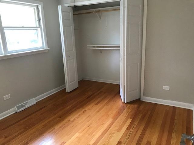 unfurnished bedroom with light wood-style flooring, a closet, visible vents, and baseboards