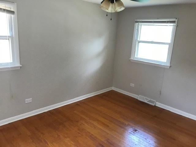 unfurnished room featuring baseboards, visible vents, and wood finished floors