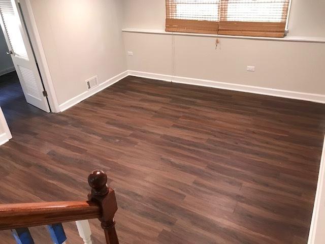 unfurnished room featuring dark wood-style floors, visible vents, and baseboards