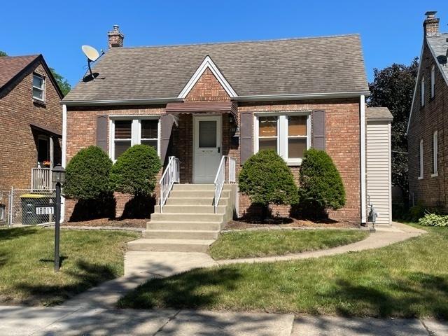 bungalow featuring brick siding, roof with shingles, and a front yard