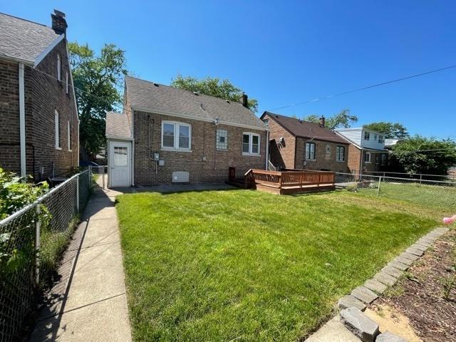 rear view of property with a deck, a yard, and a fenced backyard