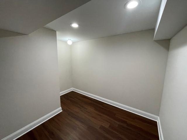 finished below grade area with dark wood-type flooring, recessed lighting, and baseboards