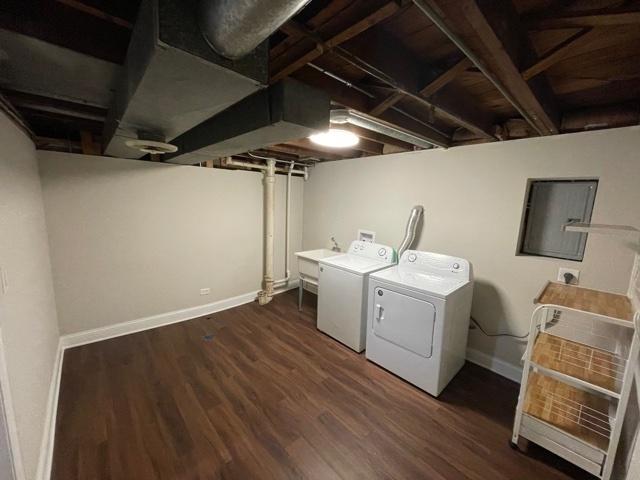 clothes washing area with laundry area, wood finished floors, washing machine and dryer, and baseboards