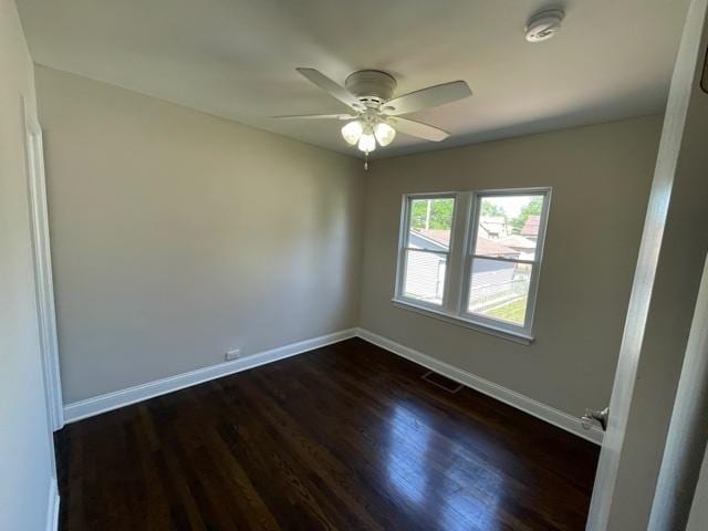 unfurnished room featuring a ceiling fan, visible vents, baseboards, and dark wood-type flooring