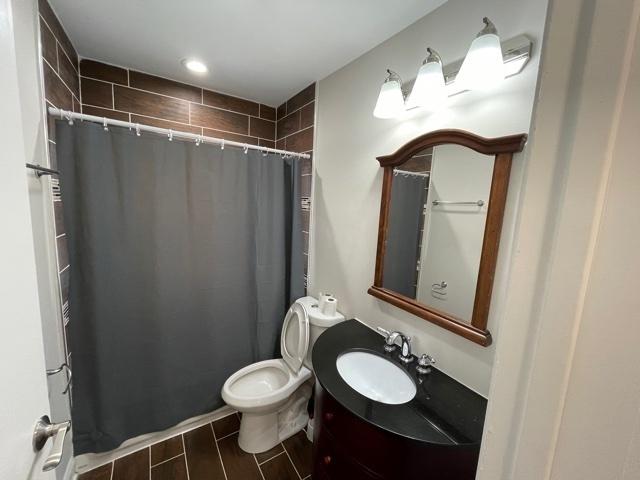 full bath with a shower with curtain, vanity, toilet, and wood tiled floor