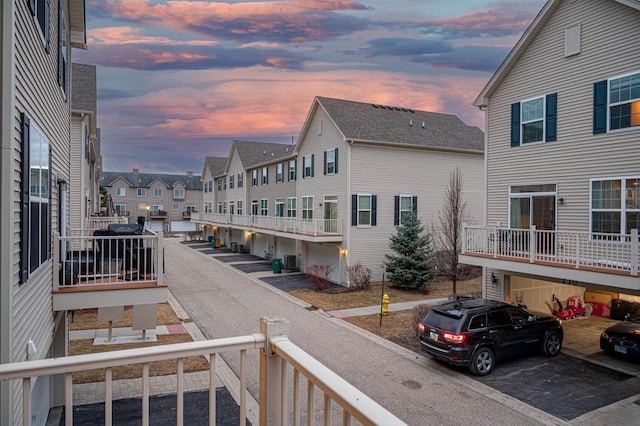 balcony at dusk featuring cooling unit and a residential view