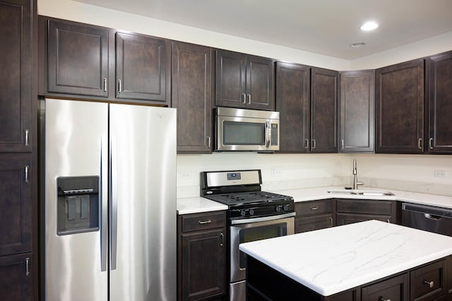 kitchen with dark brown cabinets, a center island, recessed lighting, appliances with stainless steel finishes, and a sink