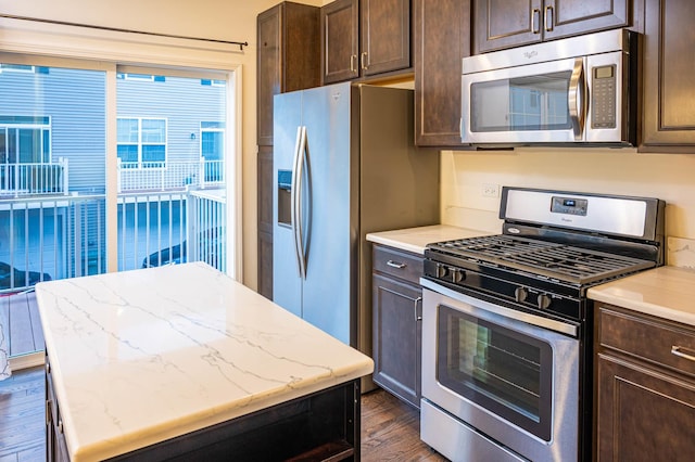 kitchen with dark wood-style floors, dark brown cabinets, appliances with stainless steel finishes, and a kitchen island