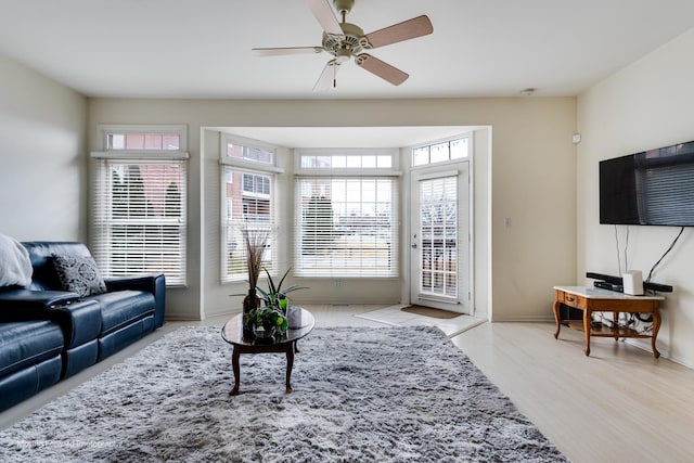 living room featuring light wood-style floors, baseboards, and a ceiling fan