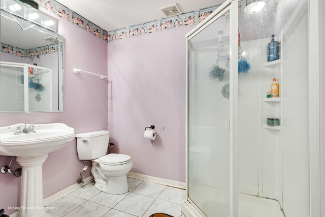 full bathroom featuring toilet, a stall shower, a sink, baseboards, and tile patterned floors