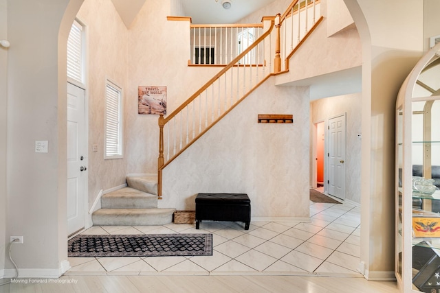 foyer featuring stairway, a high ceiling, and arched walkways