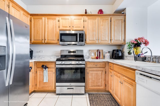 kitchen featuring light tile patterned floors, stainless steel appliances, light countertops, light brown cabinets, and a sink