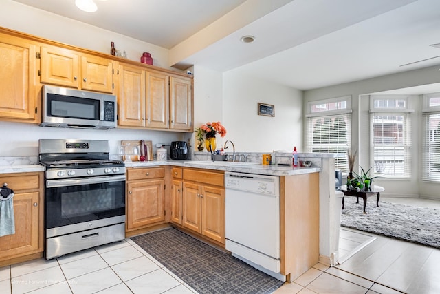 kitchen with stainless steel appliances, light countertops, a sink, and a peninsula