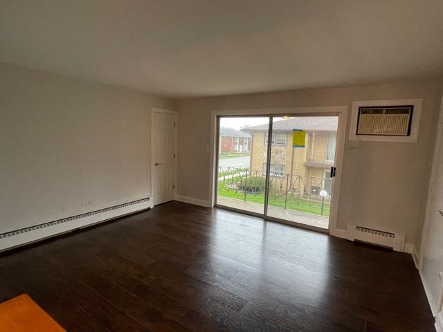 empty room with a wall mounted air conditioner, dark wood finished floors, and baseboard heating