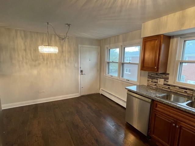 kitchen with a baseboard heating unit, dark wood finished floors, a healthy amount of sunlight, and dishwasher