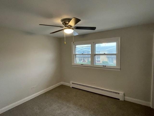 spare room with dark carpet, a baseboard radiator, and baseboards