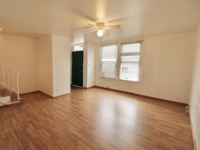 spare room featuring a ceiling fan, stairs, baseboards, and wood finished floors