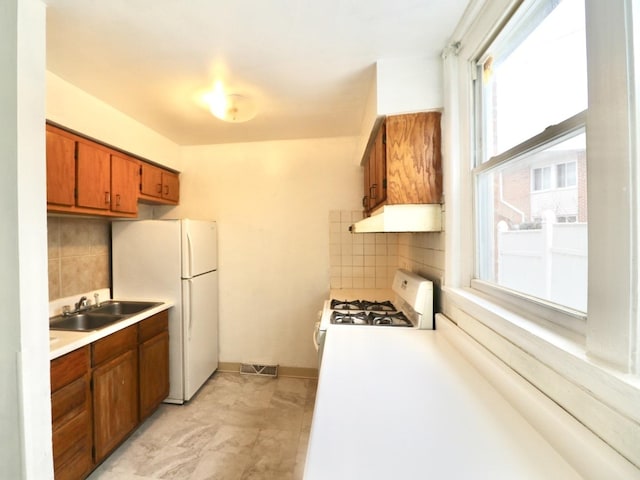 kitchen featuring white appliances, light countertops, a sink, and under cabinet range hood