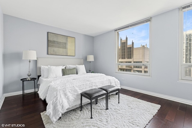 bedroom with a view of city, baseboards, and dark wood finished floors